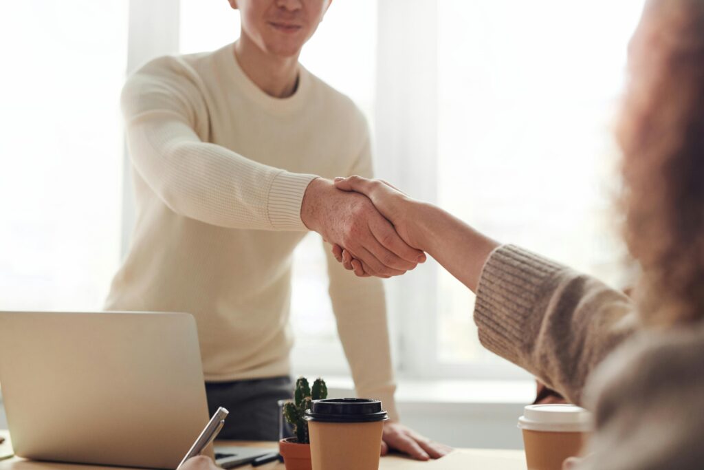 pexels photo 3184465 3184465 Close-up of professionals shaking hands over coffee in a modern office.